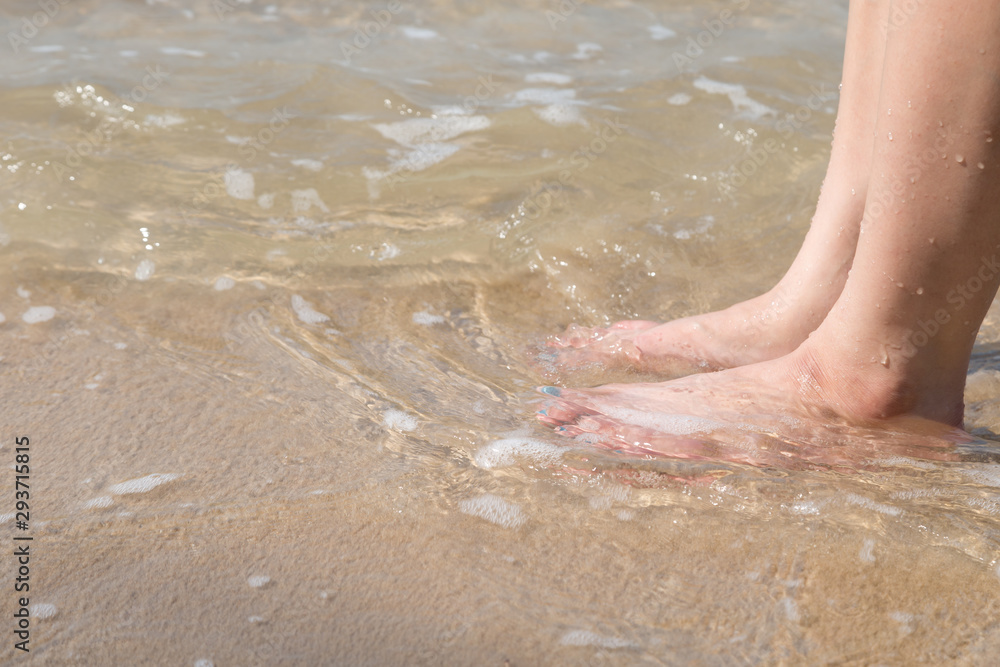 woman foot on the sand beach with sea water