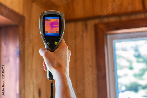 Indoor damp & air quality (IAQ) testing. A close up view on the rear screen of an infrared thermovision camera in the hand of a home inspector, pointing towards heat spot in residential ceiling.