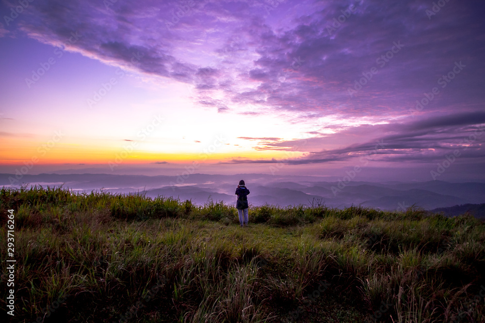 sunrise on mountain with woman standing in background