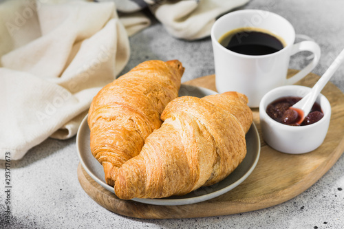 Croissants on a plate with coffee and strawberry jam. pastries for Breakfast