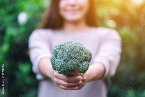 a woman holding and giving a green broccoli in hands