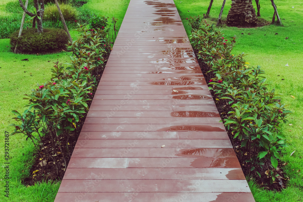 The reddish brown wooden walkway after rain in the garden.