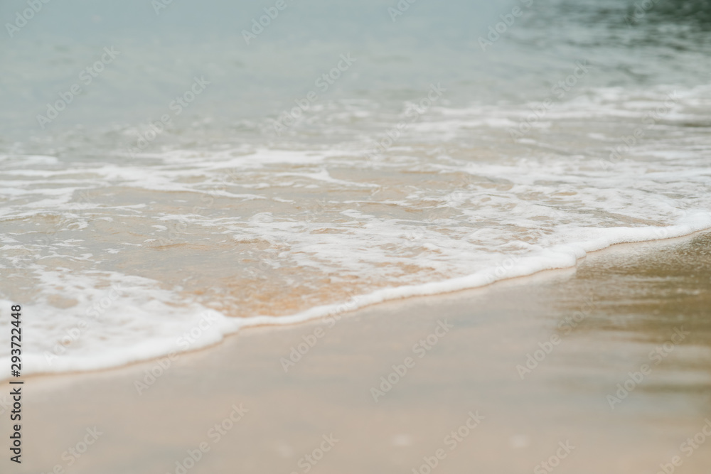 Soft waves with foam of ocean on the sandy beach background