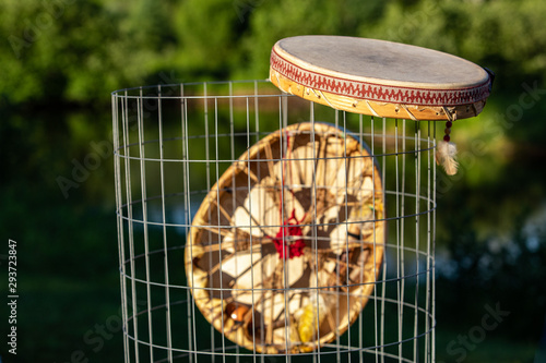 Sacred drums during spiritual singing. Two Native American hand drums are seen closeup, hanging from a mesh waste bin in a park during summer for a cultural music gathering.