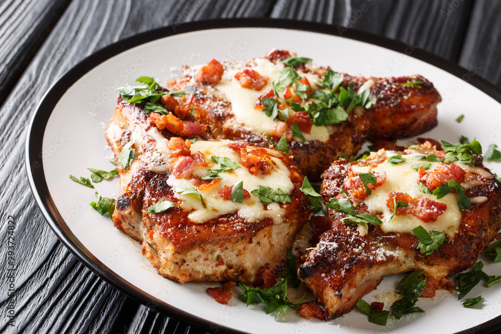 Spicy fried pork chops with melted cheese and bacon closeup on a plate on the table. horizontal Spicy fried pork chops with melted cheese and bacon closeup on a plate on the table. horizontal