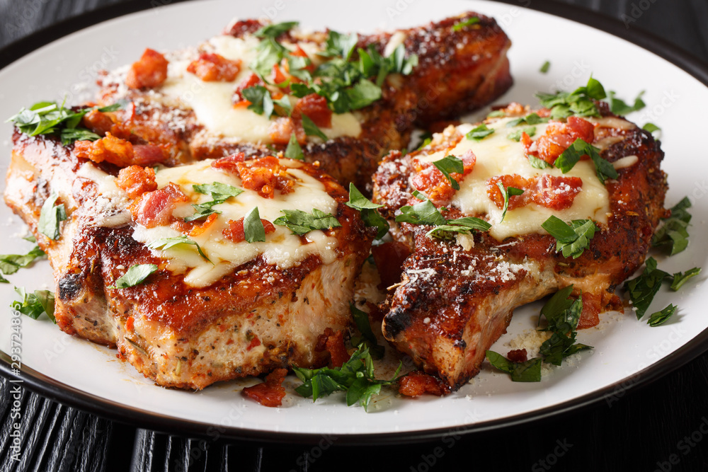 Cooked juicy pork chops with parmesan and bacon closeup on a plate. horizontal Cooked juicy pork chops with parmesan and bacon closeup on a plate. horizontal