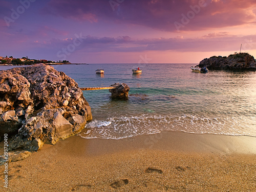 Beautiful sandy beach with rocks in the sea, small bridge and  boats at dusk time, Stoupa, Peloponnese, Greece. photo