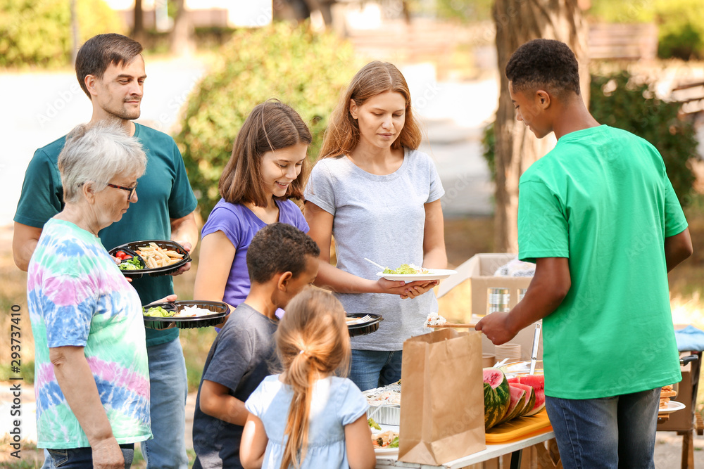 Obraz premium African-American volunteer giving food for poor people outdoors
