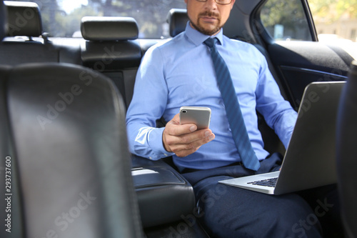 Successful businessman with laptop and mobile phone in modern car © Pixel-Shot