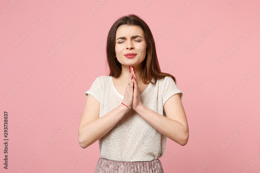 Young woman in casual light clothes posing isolated on pastel pink wall background, studio portrait. People lifestyle concept. Mock up copy space. Holding hands folded in prayer, keeping eyes closed. Young woman in casual light clothes posing isolated on pastel pink wall background, studio portrait. People lifestyle concept. Mock up copy space. Holding hands folded in prayer, keeping eyes closed.