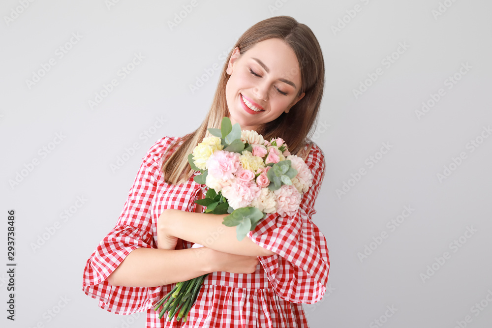 Beautiful young woman with bouquet of carnation flowers on light background Beautiful young woman with bouquet of carnation flowers on light background