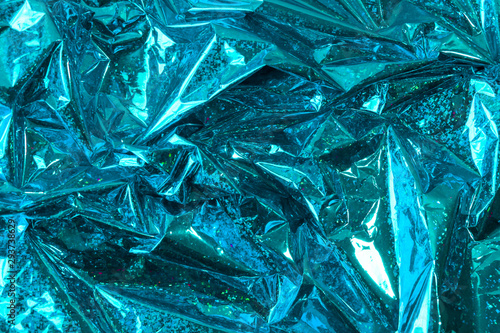 Creative photo background of blue crumpled foil with highlights and shadows