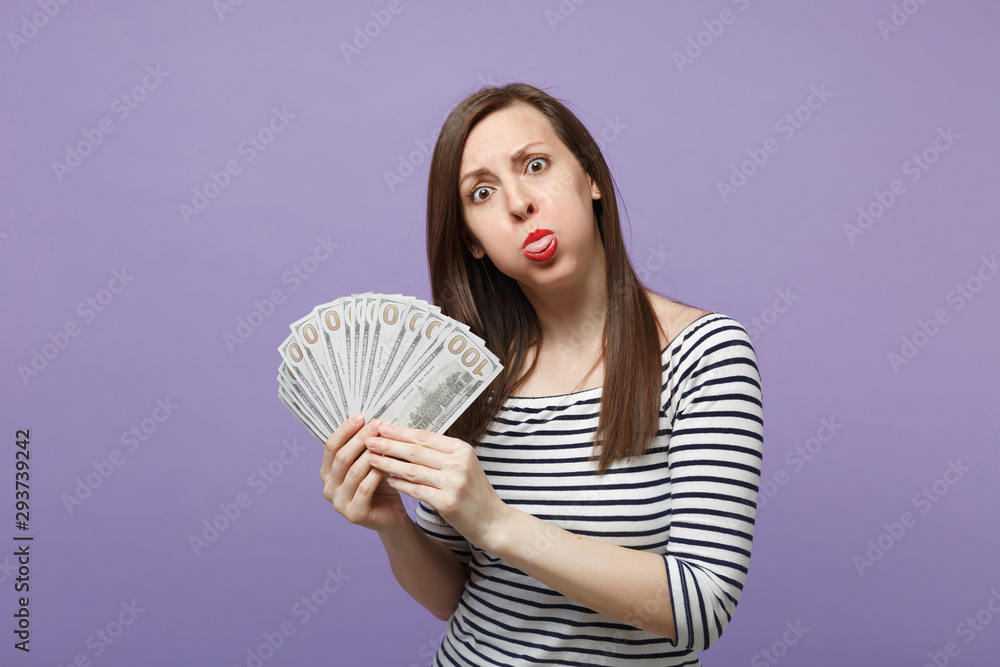 Young brunette woman girl in casual striped clothes posing isolated on violet purple background studio portrait. People lifestyle concept. Mock up copy space Hold fan of cash money in dollar banknotes Young brunette woman girl in casual striped clothes posing isolated on violet purple background studio portrait. People lifestyle concept. Mock up copy space Hold fan of cash money in dollar banknotes
