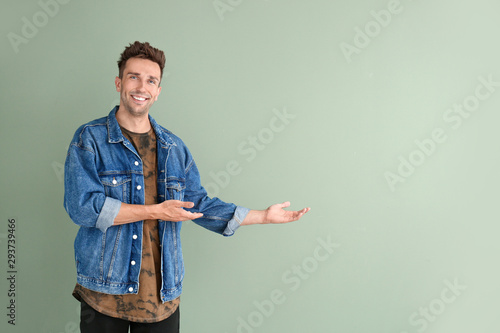 Fotografi Handsome young man showing something on color background