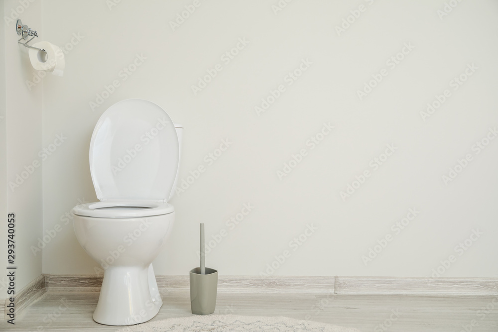 Modern ceramic toilet bowl near white wall in restroom Modern ceramic toilet bowl near white wall in restroom