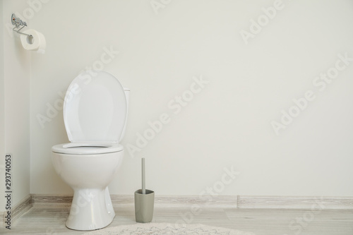 Modern ceramic toilet bowl near white wall in restroom