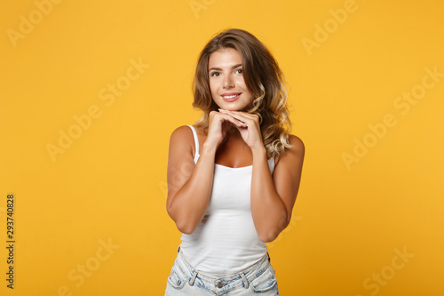 Beautiful young woman in light casual clothes posing isolated on yellow orange background, studio portrait. People sincere emotions lifestyle concept. Mock up copy space. Put hands prop up on chin.
