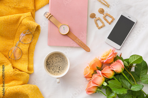 Rose flowers with mobile phone, cup of coffee and female accessories on white background