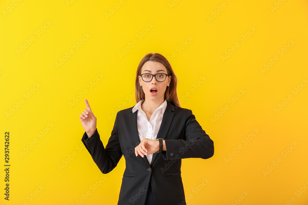 Worried young businesswoman with watch pointing at something on color background Worried young businesswoman with watch pointing at something on color background