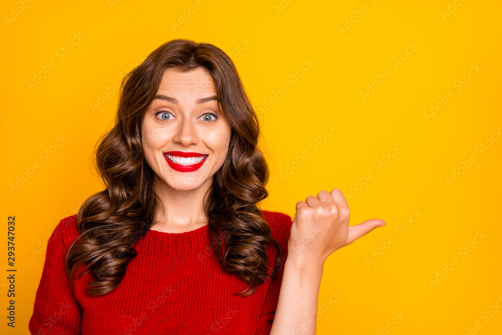 Obraz premium Photo of cheerful curly wavy charming cute girlfriend pointing at something with her finger thumb showing direction isolated over yellow vivid color background