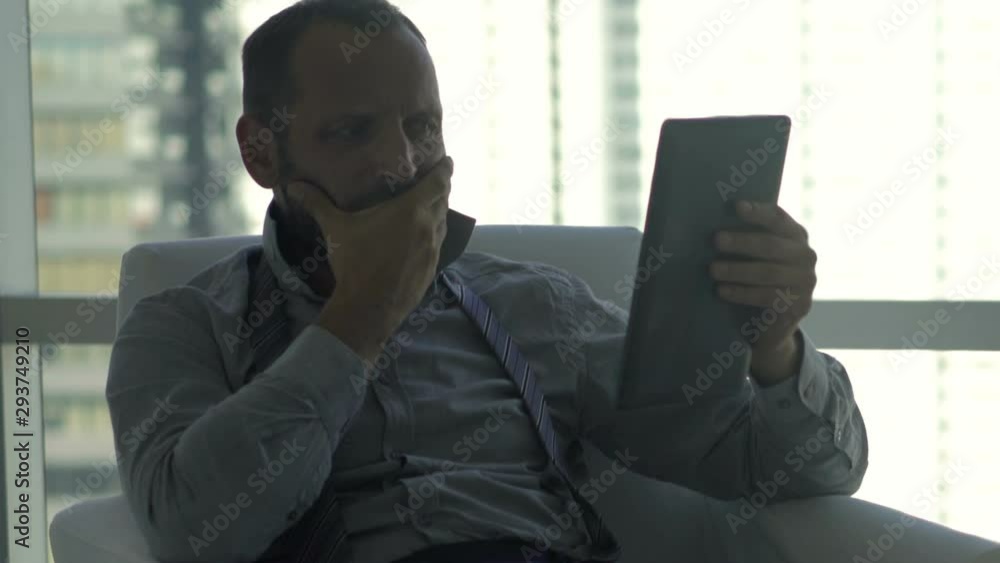 Upset businessman with tablet computer having problem sitting at home Upset businessman with tablet computer having problem sitting at home