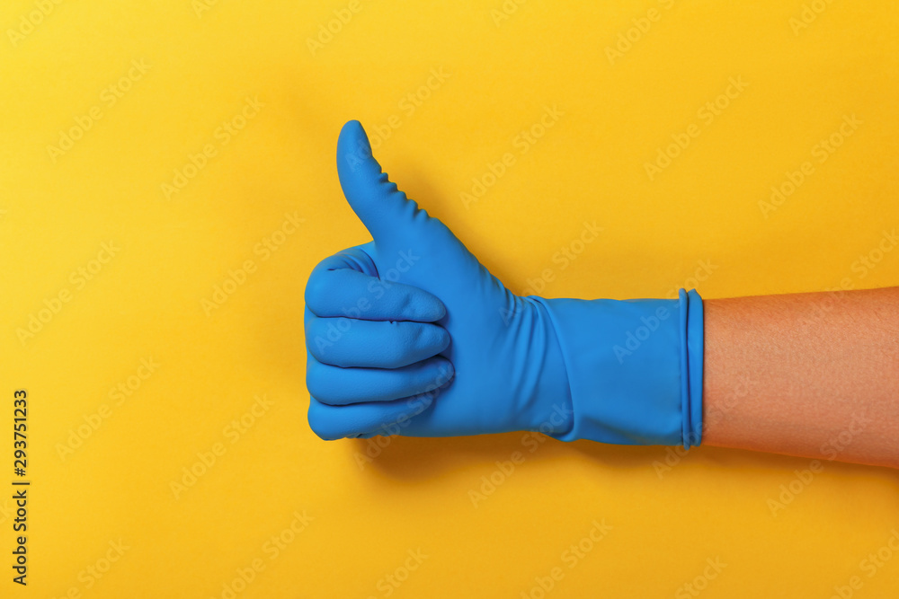 Thumb up in a blue protective glove on a yellow background