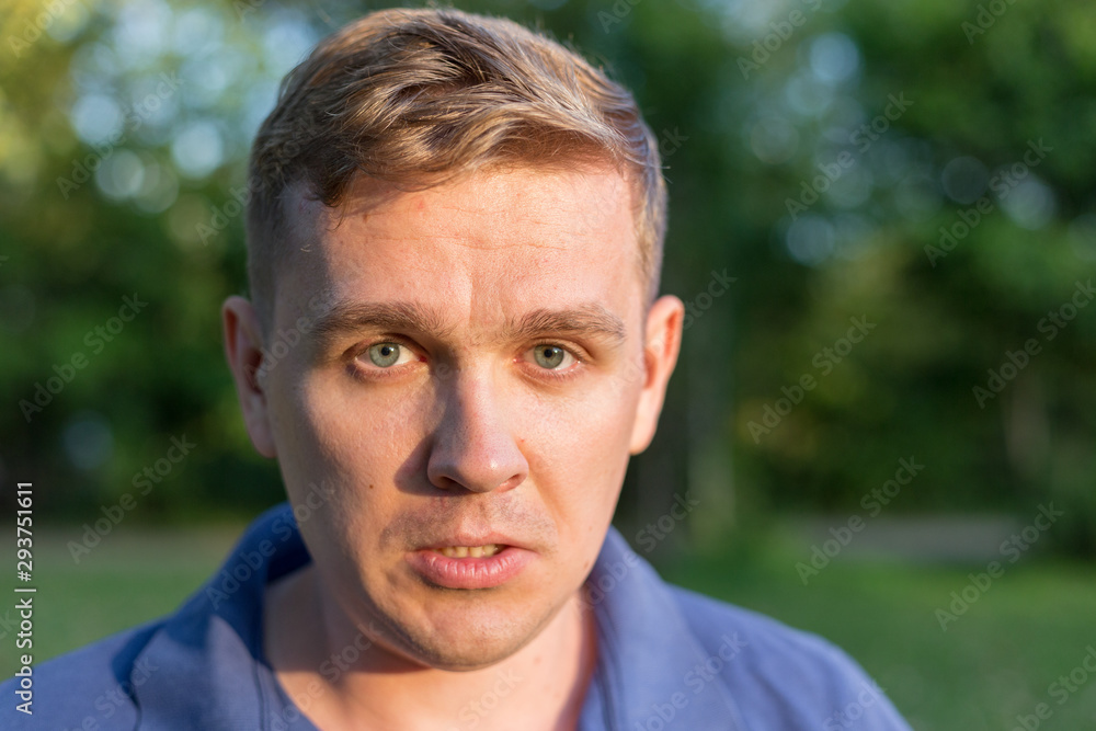 Portrait of a young guy on nature background. Puzzled confused bewildered shocked amazed man. comical reaction, emotion facial expression and feelings concept. Portrait of a young guy on nature background. Puzzled confused bewildered shocked amazed man. comical reaction, emotion facial expression and feelings concept.