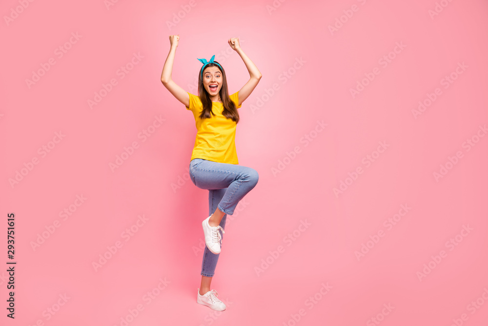 Full size photo of cheerful teen raising her fists screaming wow omg wearing yellow t-shirt isolated over pink background