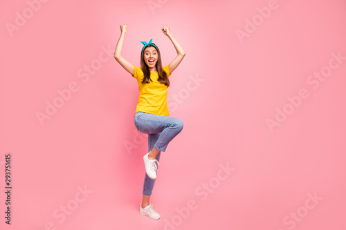 Full size photo of cheerful teen raising her fists screaming wow omg wearing yellow t-shirt isolated over pink background