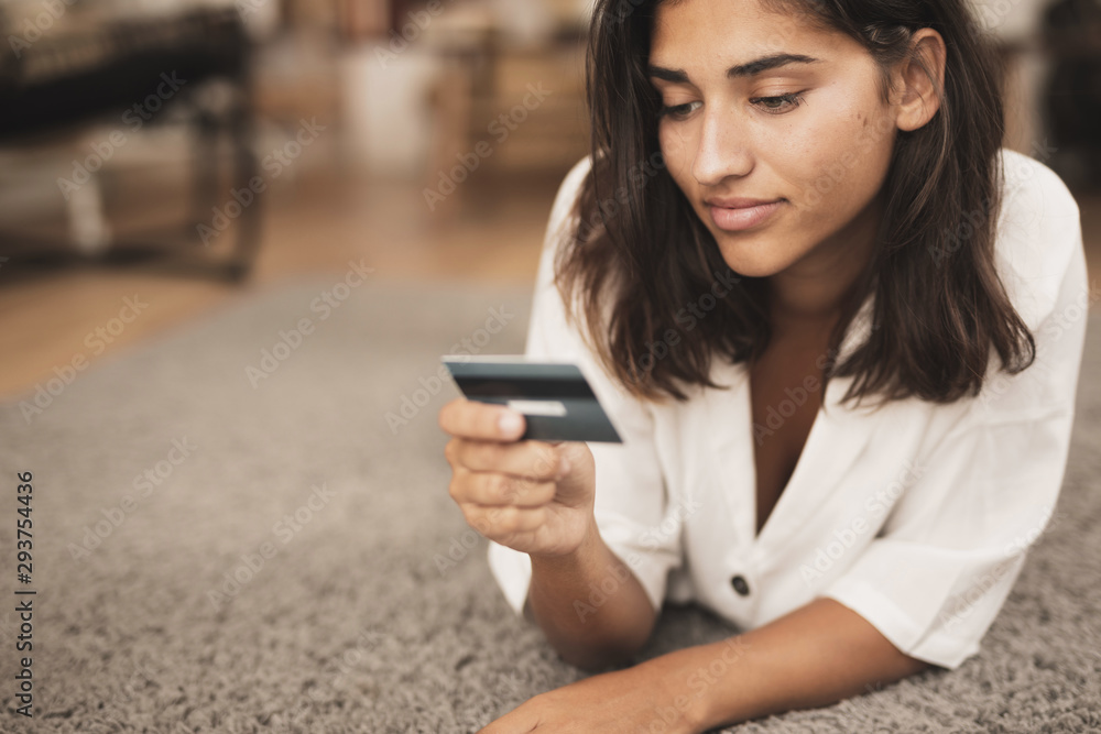 Woman sitting on floor and looking at a credit card Woman sitting on floor and looking at a credit card