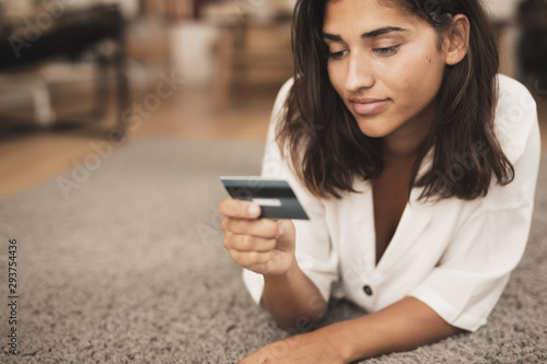 Woman sitting on floor and looking at a credit card