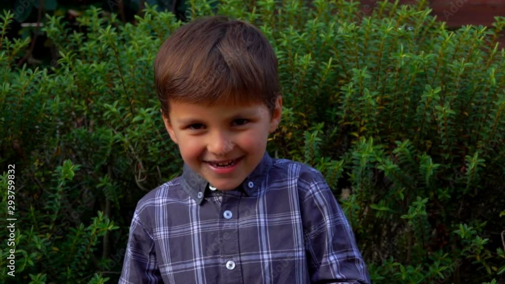 Smiling boy is playing outdoors. Five year old boy sways from side to side and smiles Smiling boy is playing outdoors. Five year old boy sways from side to side and smiles