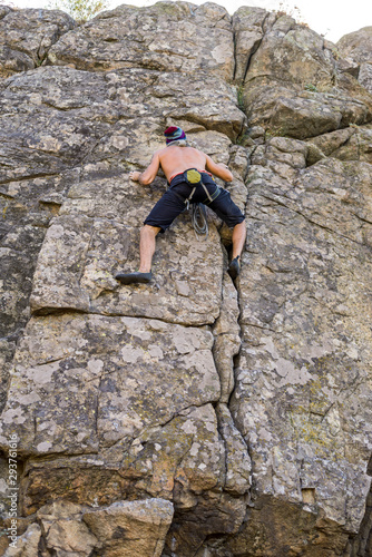 Rock climber climbs up a stone wall, rear view.