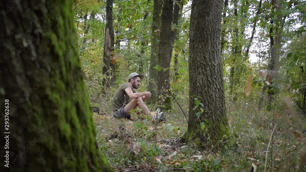 Young man smoking in an isolated forest in between trees in slow motion Young man smoking in an isolated forest in between trees in slow motion