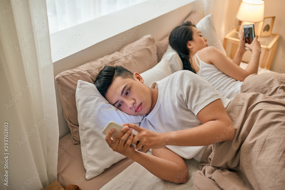 Young couple with smartphones in their bed