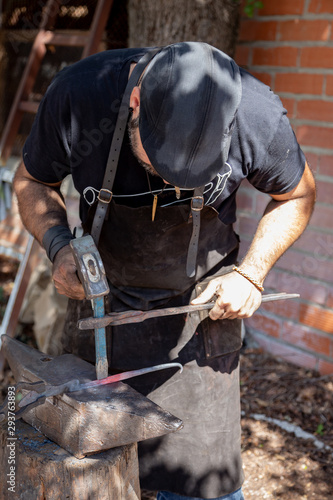 blacksmith working on an anvil. Blacksmith forging red-hot metal with hammer. Blacksmith concept © Fabio