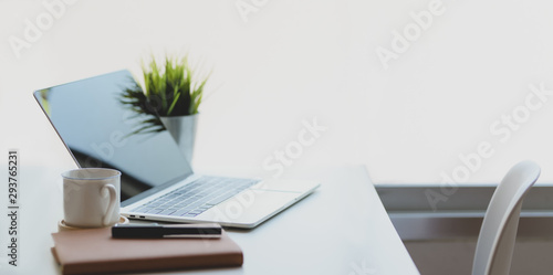 Laptop computer with coffee cup and office supplies in comfortable workplace near the windows