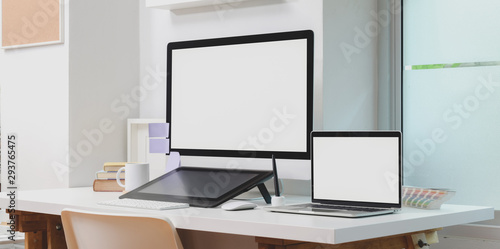 Blank screen desktop computer and laptop computer with office supplies in modern workplace