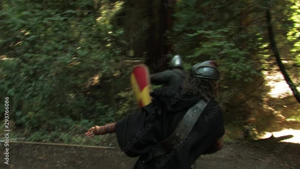 A medieval warrior battles three knights in the woods A medieval warrior battles three knights in the woods