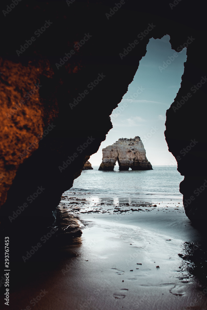 Famous rock formation framed by a cliff cave at the ocean. Praia dos Três Irmãos, Prainha in Portimão, Algarve coast in Portugal, Atlantic Ocean