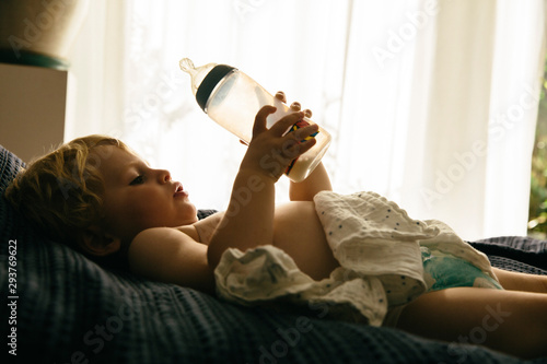 Kleiner Junge trinkt Milch aus einer Flasche photo