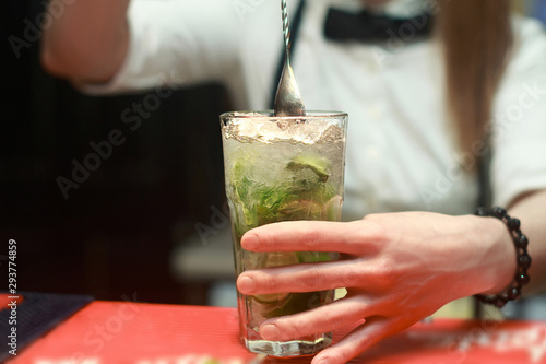 Woman barman making a mahito cocktail photo