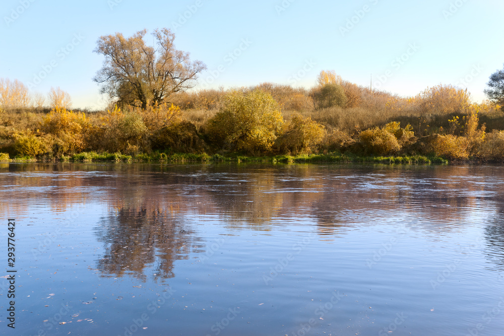Mirror reflection of the shore in a pond on a sunny autumn day Mirror reflection of the shore in a pond on a sunny autumn day