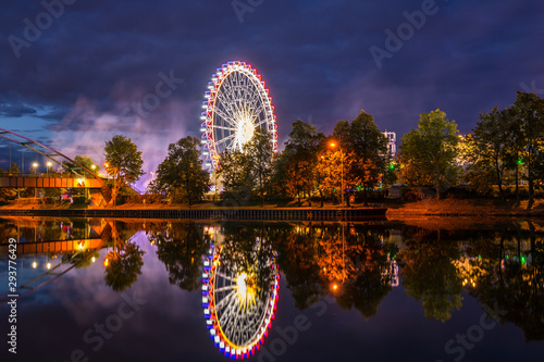 Obraz na płótnie Germany, Colorful illuminated ferris wheel and lights of giant swabian fair called cannstatter wasen in stuttgart city by night reflecting in neckar river water w salonie