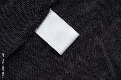 Blank white laundry care clothing label on black fabric texture