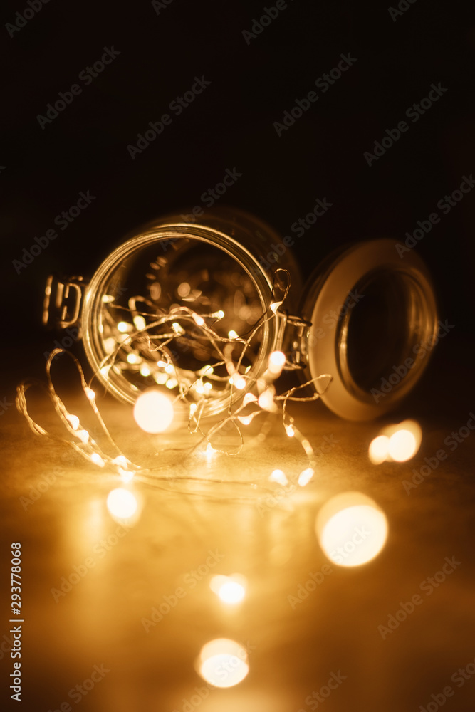 Fairy light in vintage hipster glass jar with blur bokeh dark background.