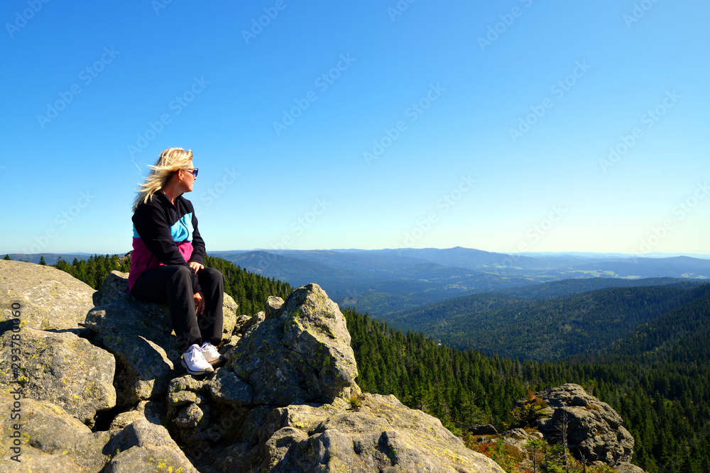 Obraz premium Hiker sitting on rock.Tourist on the top of Grosser Arber mountain in National park Bayerischer wald, Germany.