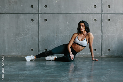 young brunette fitness woman sitting on floor in brutal concrete gym foto  de Stock | Adobe Stock