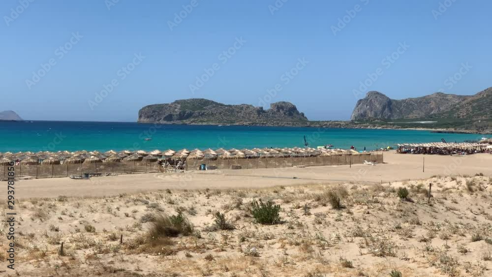 Famous paradise sandy deep turquoise beach of Falasarna in North West Crete island, Greece. People on the beach hiding from the sun in summer. Famous paradise sandy deep turquoise beach of Falasarna in North West Crete island, Greece. People on the beach hiding from the sun in summer.