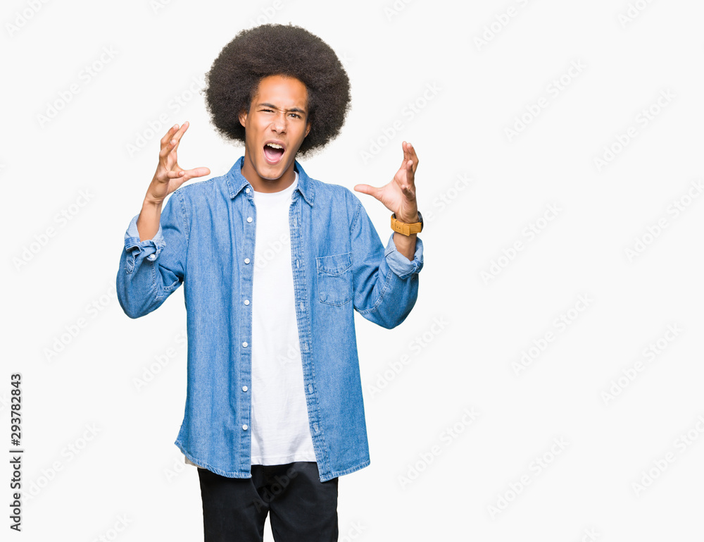 Young african american man with afro hair Shouting frustrated with rage, hands trying to strangle, yelling mad Young african american man with afro hair Shouting frustrated with rage, hands trying to strangle, yelling mad